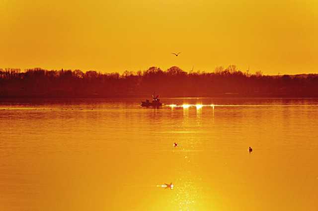 Ein Fischer kehrt im Sonnenuntergang von Wacker...