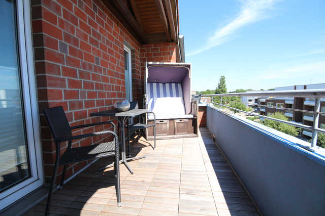 Großer Balkon mit Tisch, Stühlen und Sonnenschirm