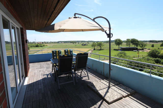 Großer Balkon mit Tisch, Stühlen und Sonnenschirm