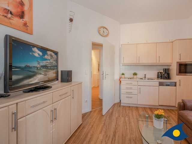 Wohnbereich mit Couch und TV sowie Küchenzeile