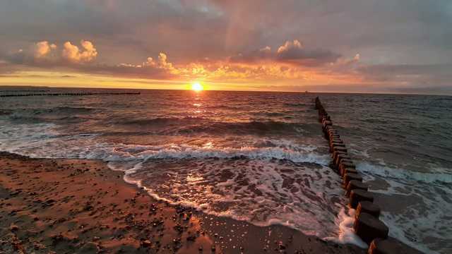 Wellen erreichen den Strand im Sonnenuntergang